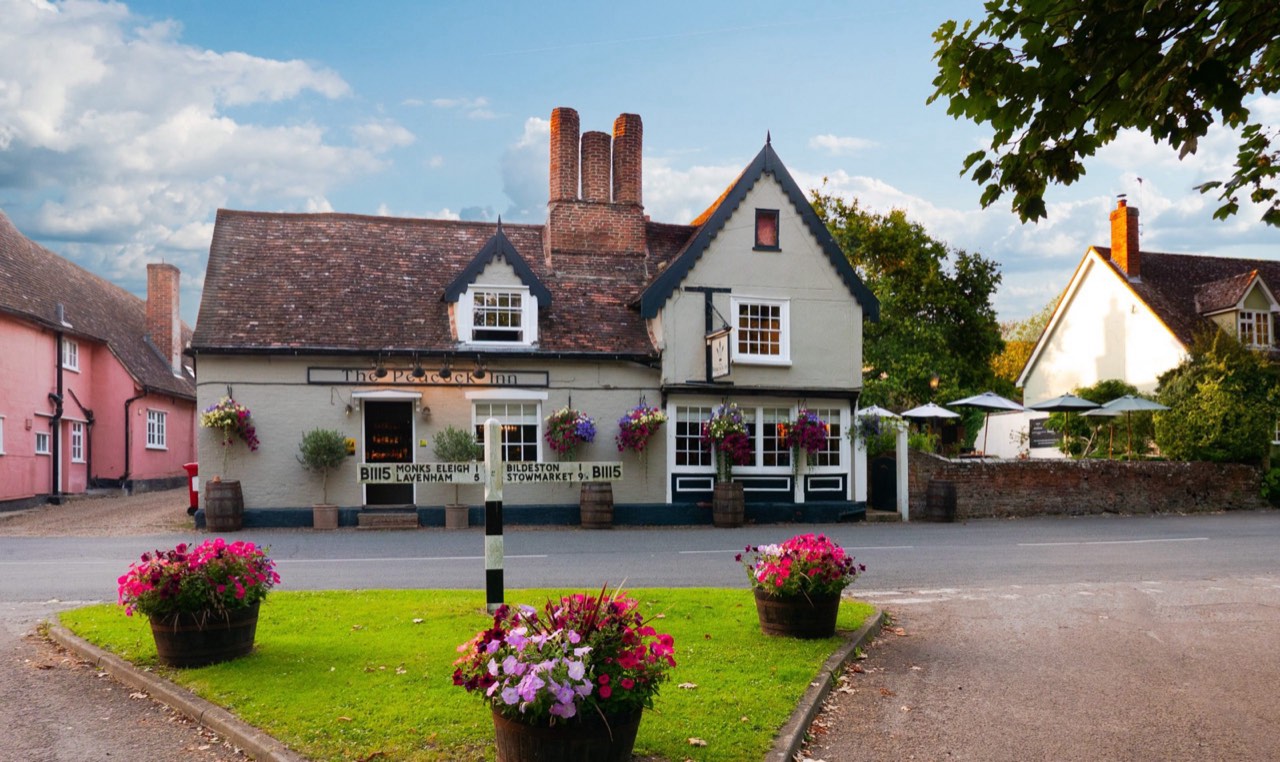 The Peacock Inn at dusk — a 14th-century timber-framed inn with hanging flower baskets in Chelsworth, Suffolk